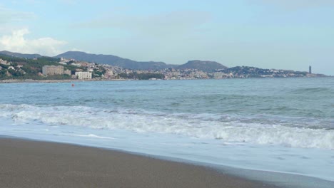 Splashing Cool Waves Of Ocean With Overview Of Cityscape In Spain Underneath A Blue Clear Sky - Wide Shot