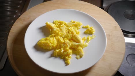 persona está sirviendo un plato con huevos revueltos, luego retira el plato