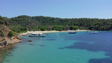 Luftaufnahme:-Flug-Zum-Strand-Der-Insel-Tsougkria,-Wo-Touristenboote-Und-Segelboote-Vor-Anker-Liegen