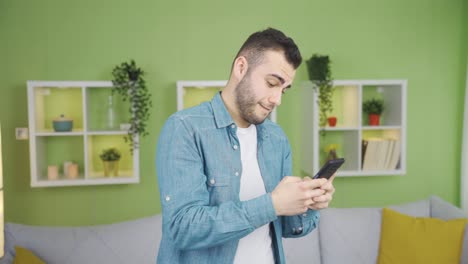 Happy-and-relaxed-young-man-using-phone-at-home.