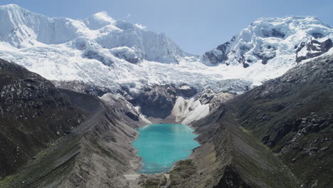 Stunning-aerial-view-of-a-turquoise-lake-surrounded-by-snowy-mountains-and-glaciers-in-an-alpine-landscape