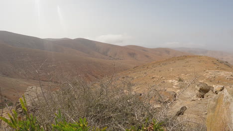 mountain desert landscape view from hillside slope with few growing plants in fuerteventura, canary islands, spain