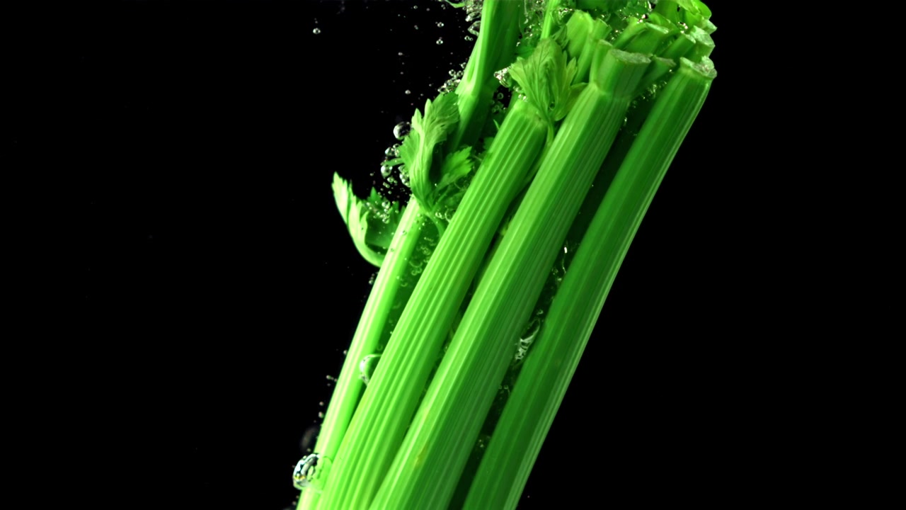 Fresh Green Celery Dropping into Water in Slow Motion