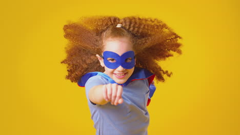 studio portrait of girl dressed as comic book superhero against yellow background