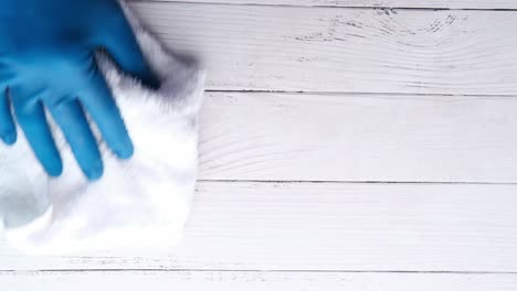 cleaning a white wooden surface with blue gloves and a white cloth