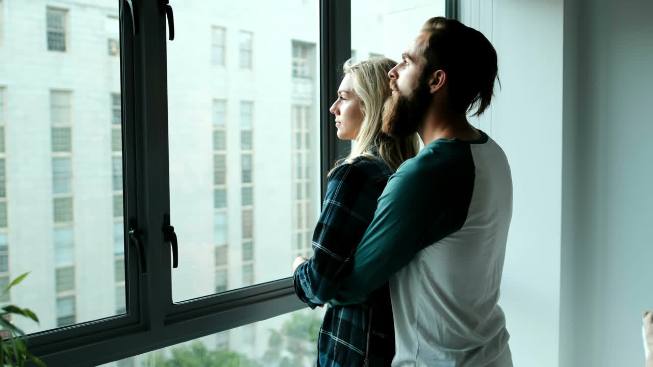 Couple looking through window at home 4k