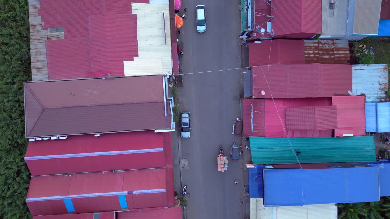 Motorcycles driving on a busy road in a street market in Areiksart Port village, Cambodia, at sunset. Marvelous aerial view flight vertical bird's eye view drone