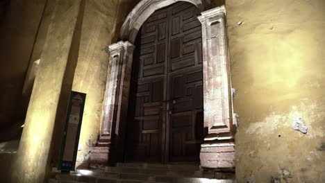 a huge wooden door with dull paint on the all at night