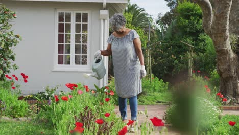 Animation-of-african-american-senior-woman-gardening,-watering-flowers