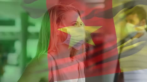 Animation-of-flag-of-cameroon-waving-over-woman-wearing-face-mask-during-covid-19-pandemic