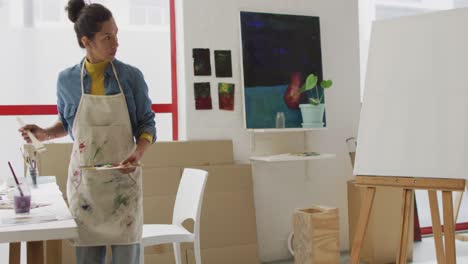 video de una artista biracial pintando en un estudio