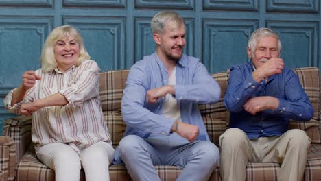 Familia-De-Generación-Feliz-De-Abuelos-Mayores-Con-Un-Hijo-Adulto-Escuchando-Música,-Bailando-En-Casa