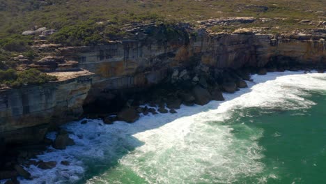 ocean coastline with breaking waves on cliffside at royal national park in sydney, new south wales, australia