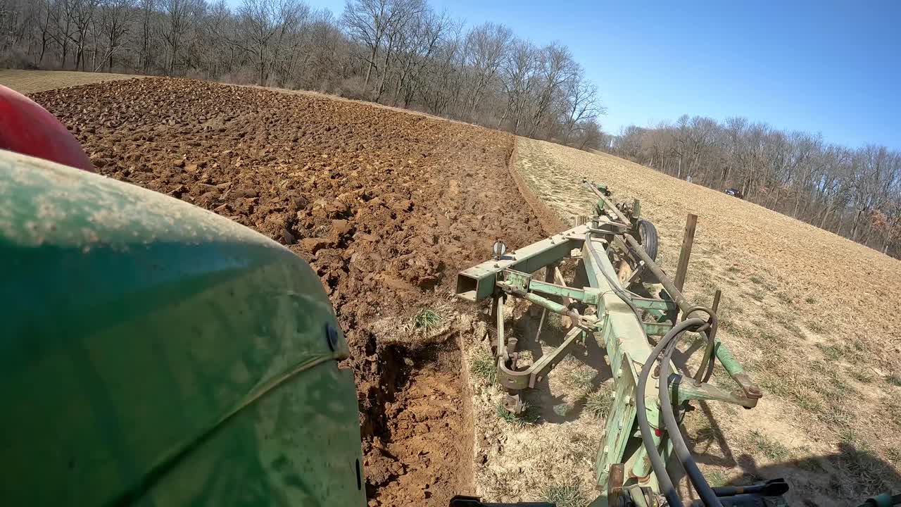 - pov agricultor en tractor agrícola verde usando un arado para preparar un campo a principios de la primavera en el medio oeste