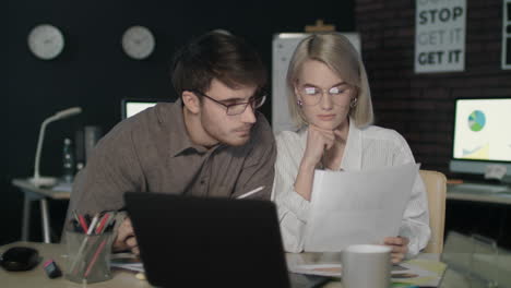 business couple watching together financial report front computer in dark office