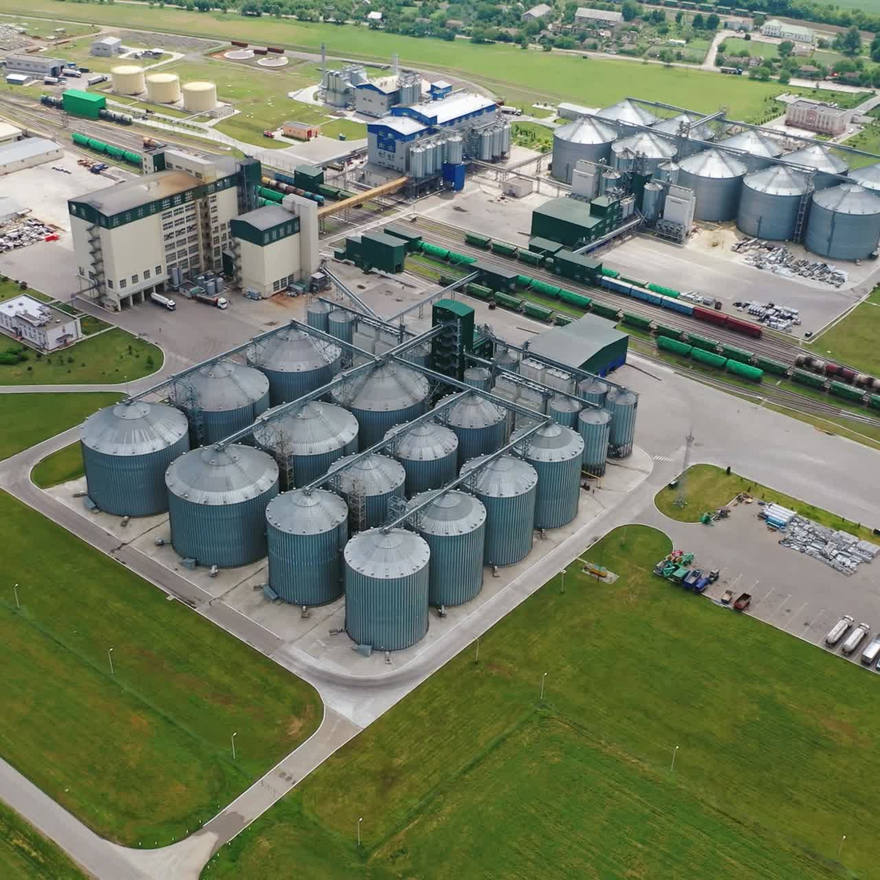Large granary on field. Granary warehouse aluminum containers for storing grains. Elevators among nature. Aerial view.