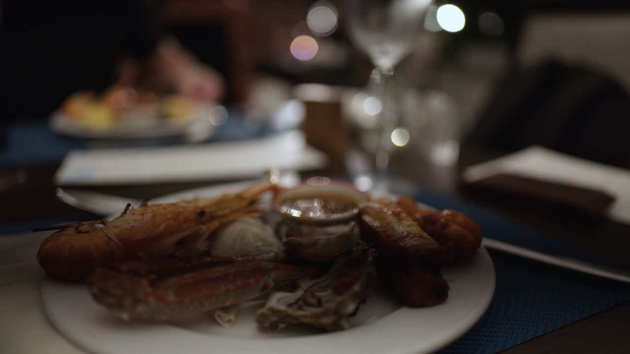 Plated shrimp, oyster, and crab in dimly lit restaurant, shallow focus, elegant dining atmosphere