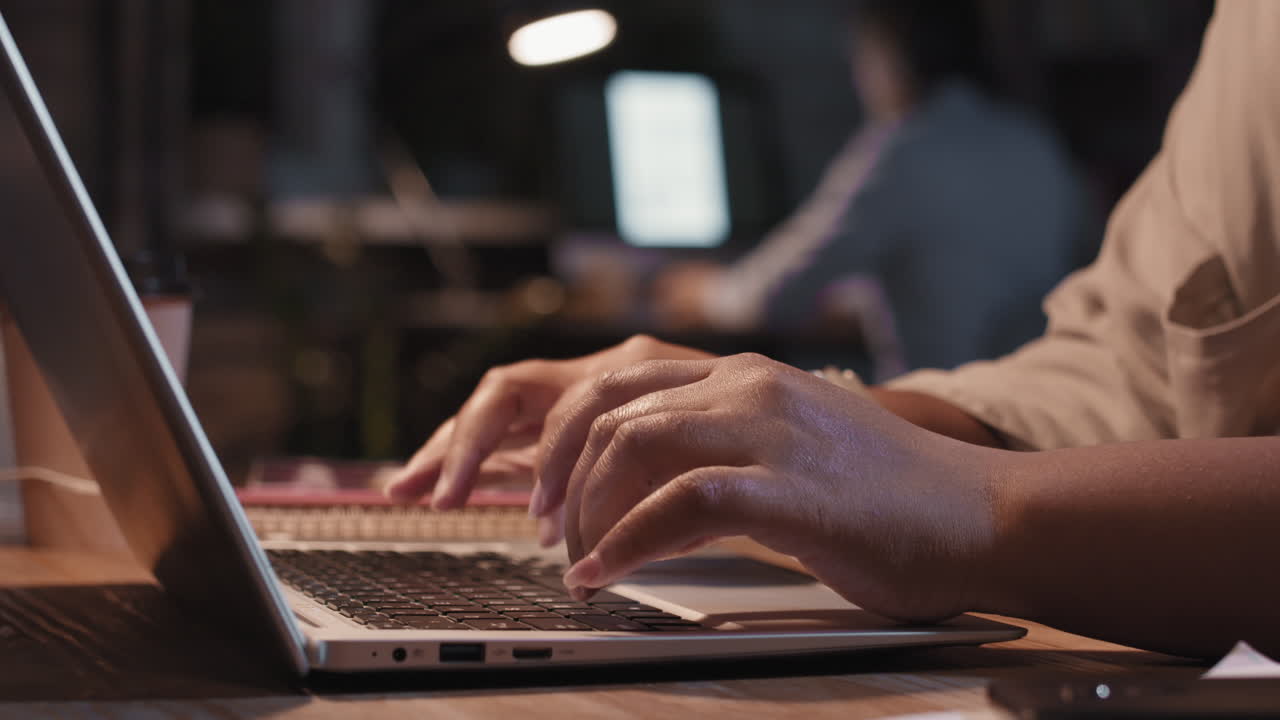 Close-up van handen die typen op een laptoptoetsenbord in een kantooromgeving