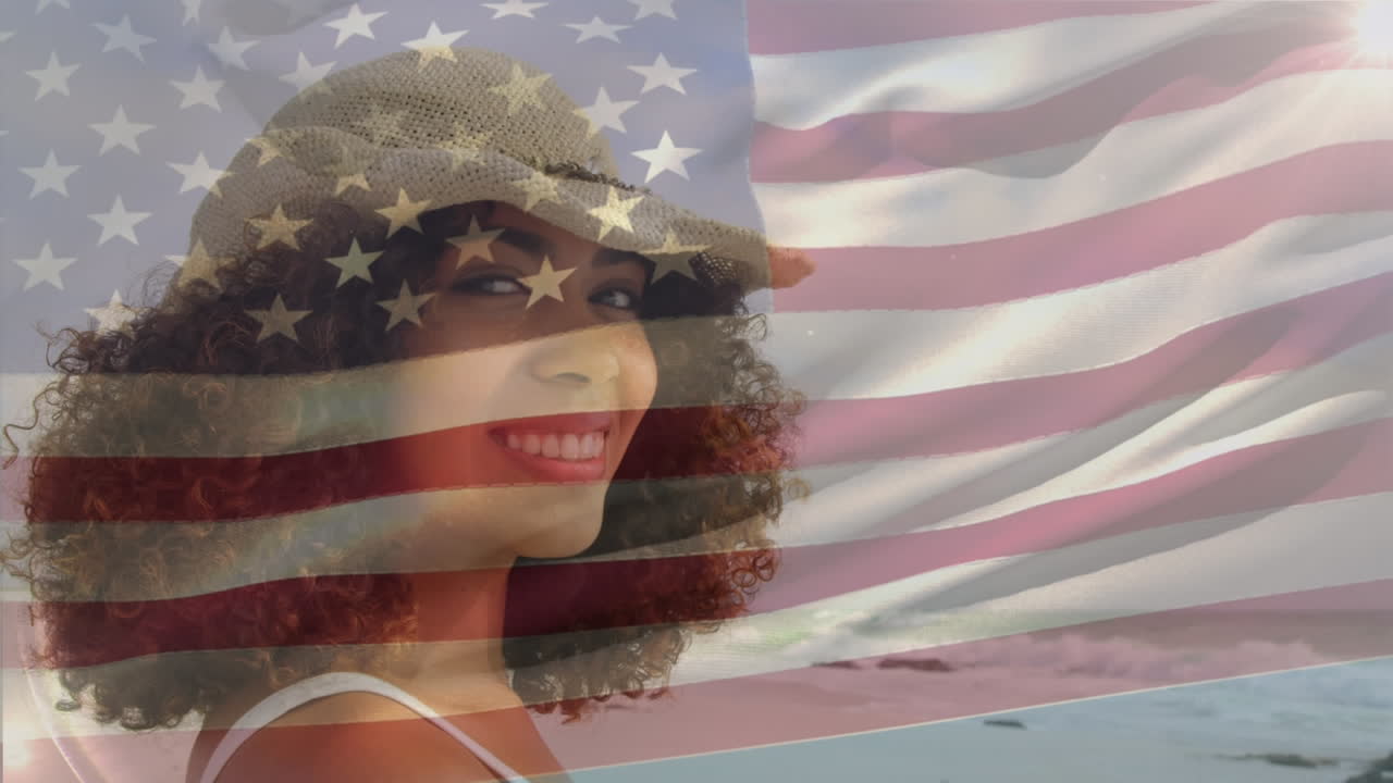 animación de la bandera de américa ondeando sobre una mujer afroamericana sonriente disfrutando de la brisa en la playa
