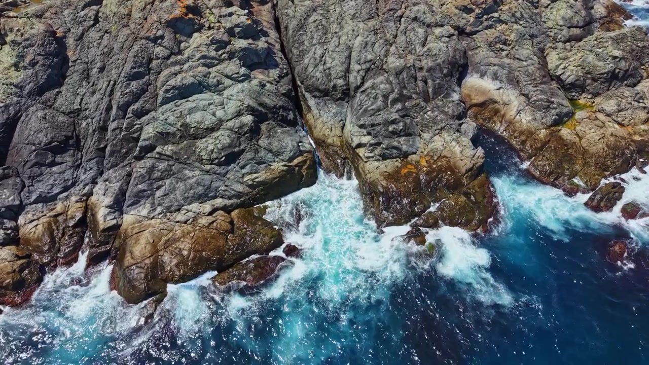 Onde si infrangono contro la costa rocciosa vicino alla zona costiera durante una giornata luminosa e soleggiata