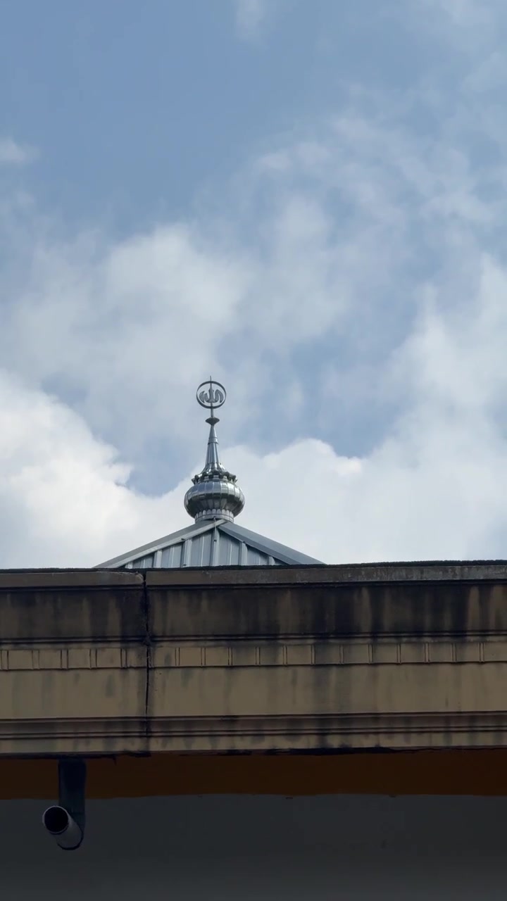 Sølv moskékuppelspir mod en skyet blå himmel
