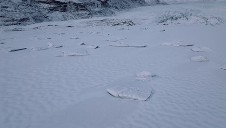 Aerial-view-over-iceberg-frozen-inside-Skaftafellsjokull-glacier-covered-in-snow,-Iceland