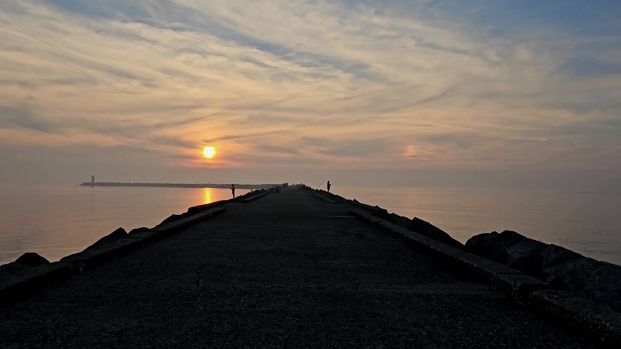 Una tarde tranquila con vista al atardecer en un muelle con la silueta de un pescador a lo lejos. Este metraje es ideal para relajación, actividades al aire libre, vistas al atardecer, viajes, vacaciones y temas cinematográficos.