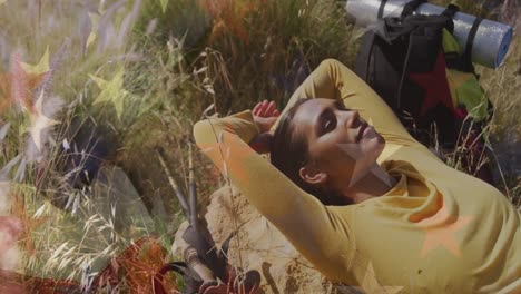 Animation of flag of united states of america over woman relaxing in nature