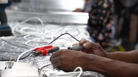 skilled hands soldering cables at a workbench preparing them for further soldering