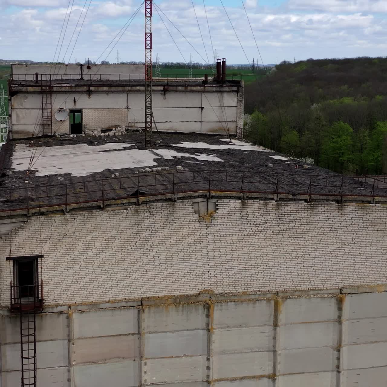 Ruined large building of a factory on green nature background. Old industrial plant with abandoned building. Abandoned factory