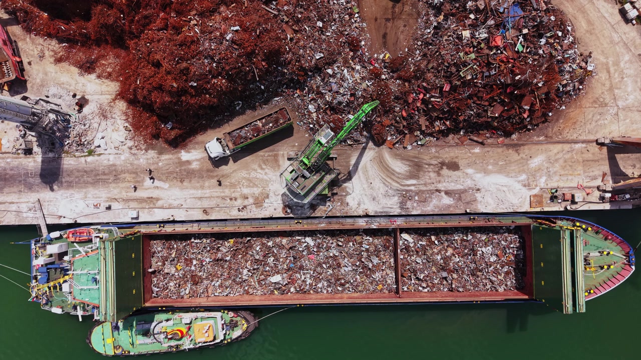 Una nave da carico carica rottami metallici presso un impianto di riciclaggio nel pomeriggio