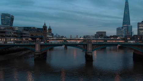 Dolly-back-drone-shot-of-traffic-on-southwark-bridge-at-sunset-blue-hour