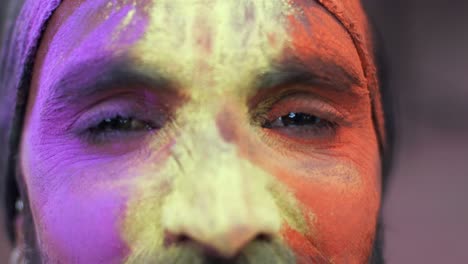 indian man close-up of face smeared with bright holi colors