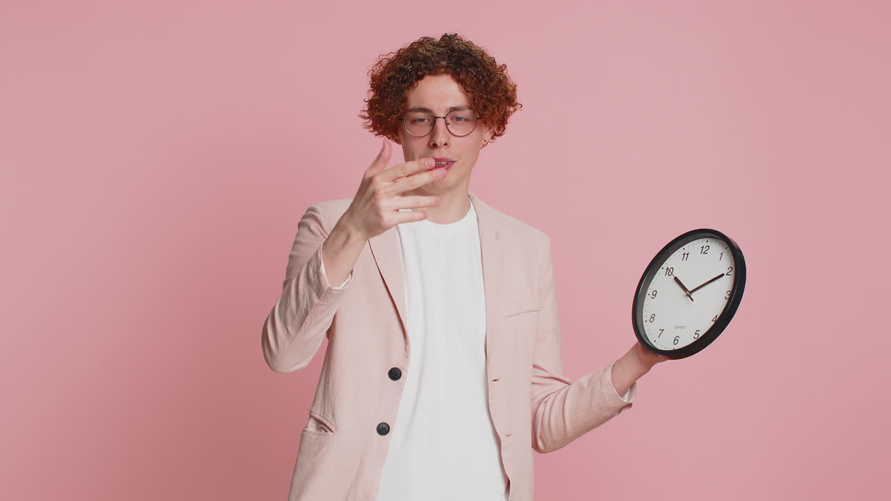 hombre caucásico emocionado mostrando la hora hora en el reloj de la oficina de la pared ok pulgar hacia arriba aprobar apresurarse plazo
