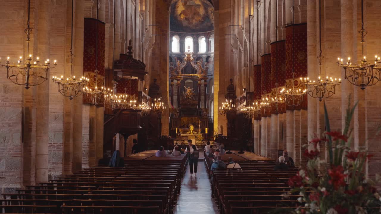 Interior of a grand basilica with people praying