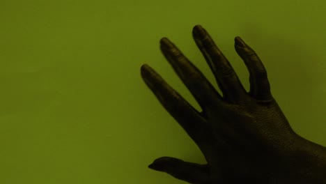 young female hand painted with black color moving smoothly in a green background