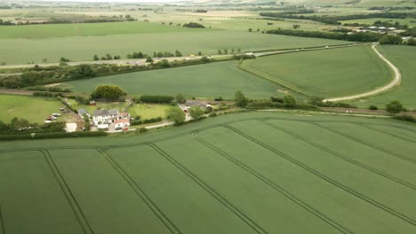 aerial orbit of rural farming crop fields with house and country lanes