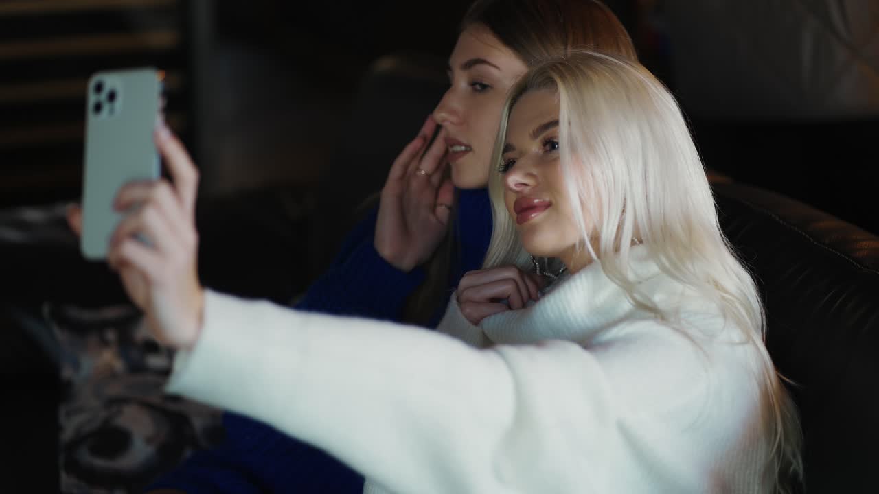 Due ragazze attraenti scattano foto con la fotocamera dello smartphone e posano.