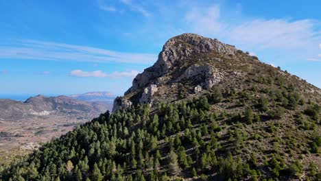 imágenes de drones panorámicos de una montaña boscosa y rocosa de montserrat en calpe, españa, con un hermoso cielo azul y un paisaje nuboso en el fondo