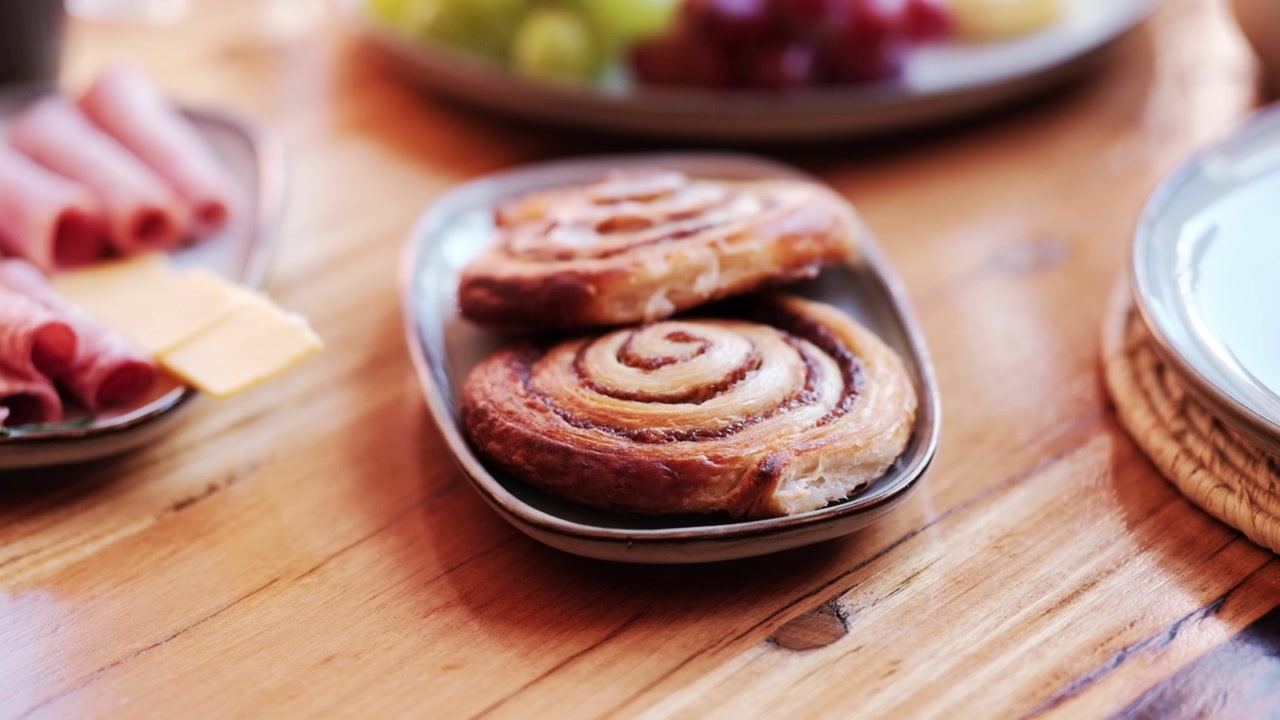 Two pastry swirls on a plate at a breakfast spread
