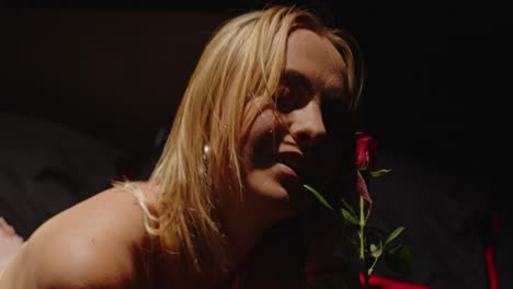 blonde woman's intimate moment with a red rose