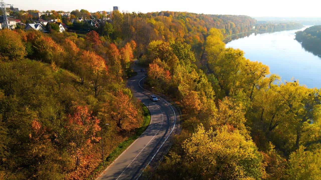 fotografía de un automóvil conduciendo en una carretera sinuosa adyacente al ferrocarril a lo largo del río nemunas en kaunas, lituania, zoom en la toma