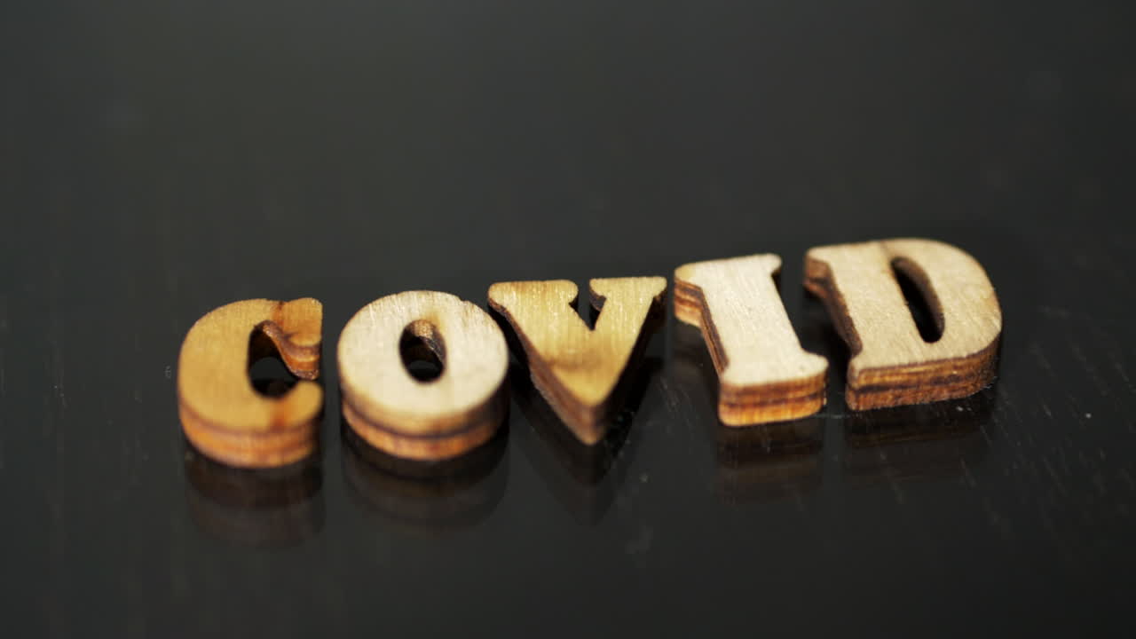 palabra o título de virus covid escrito en letras de madera sobre fondo oscuro, disparo en órbita