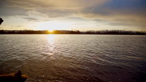 Sonnenuntergang-Am-Strand-Eines-Großen-Flusses,-Mit-Leuchtenden-Farben,-Die-Sich-Im-Wasser-Spiegeln-Und-Eine-Heitere-Und-Malerische-Szenerie-Schaffen,-Die-Natürliche-Schönheit-Und-Ruhige-Atmosphäre-Vereint