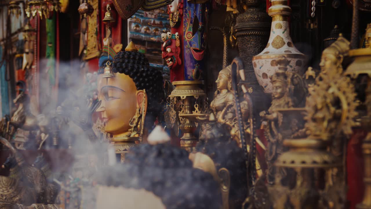 Humo de incienso elevándose entre estatuas doradas de Buda y objetos asiáticos