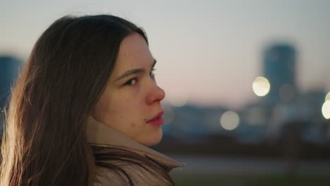 close-up of a girl's side profile with a faint smile, set against a blurred background, evoking a sense of gentle warmth and subtle emotion