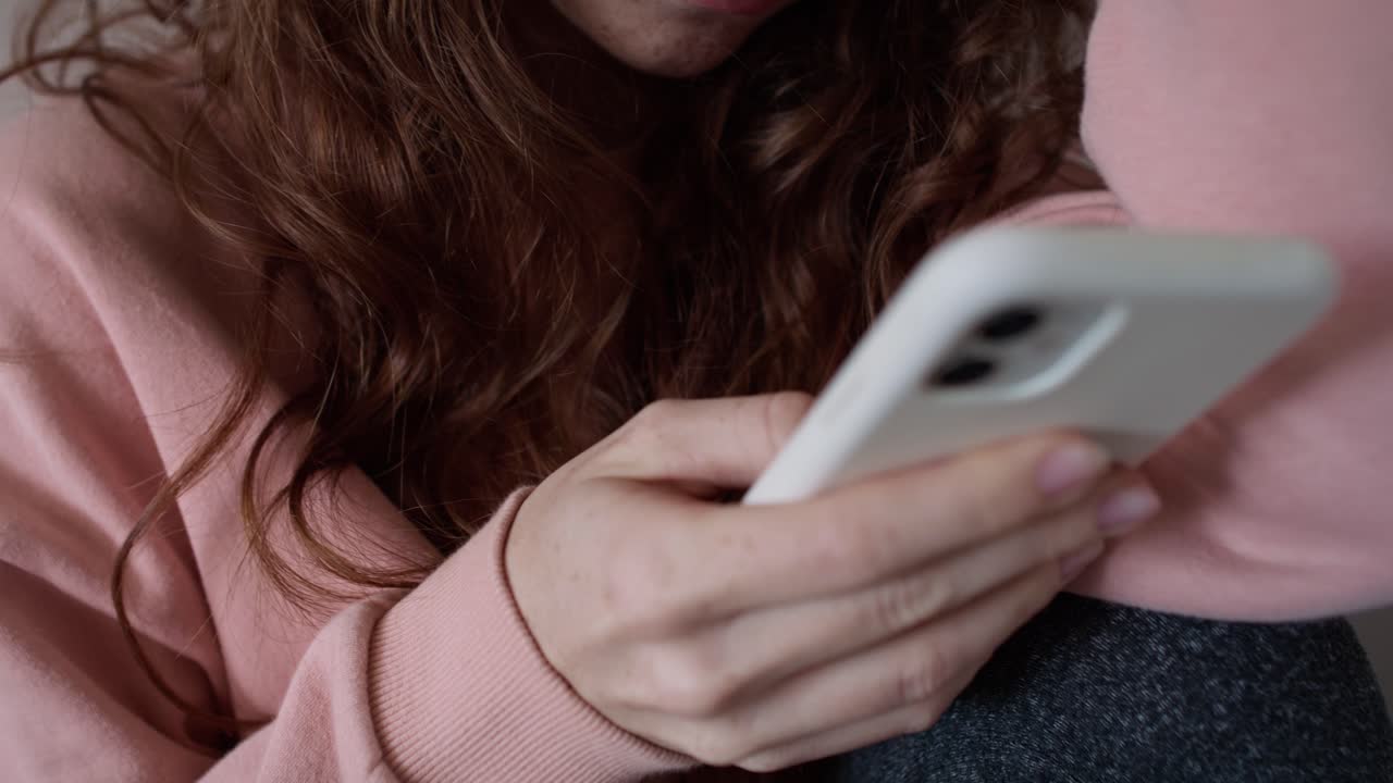 video de cerca y de mano de una joven mujer caucásica usando un teléfono móvil.