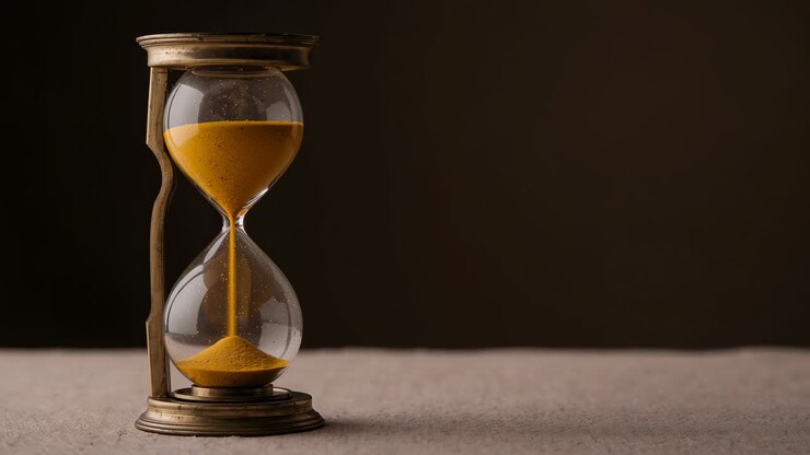 Showing antique hourglass moving yellow sand on studio surface, running due to gravity, copy space