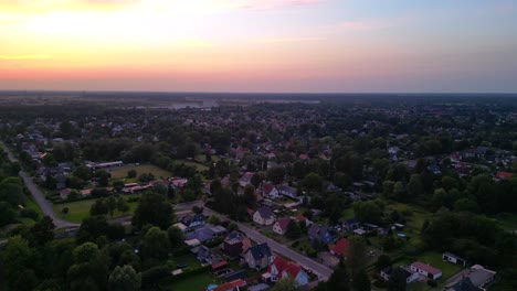 sunset residential area in brandenburg, germany, showcasing rooftops, lush greenery, and a network of roads. smooth aerial view flight panorama overview drone