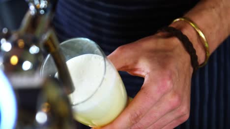 camarero vertiendo cerveza del grifo de la cerveza